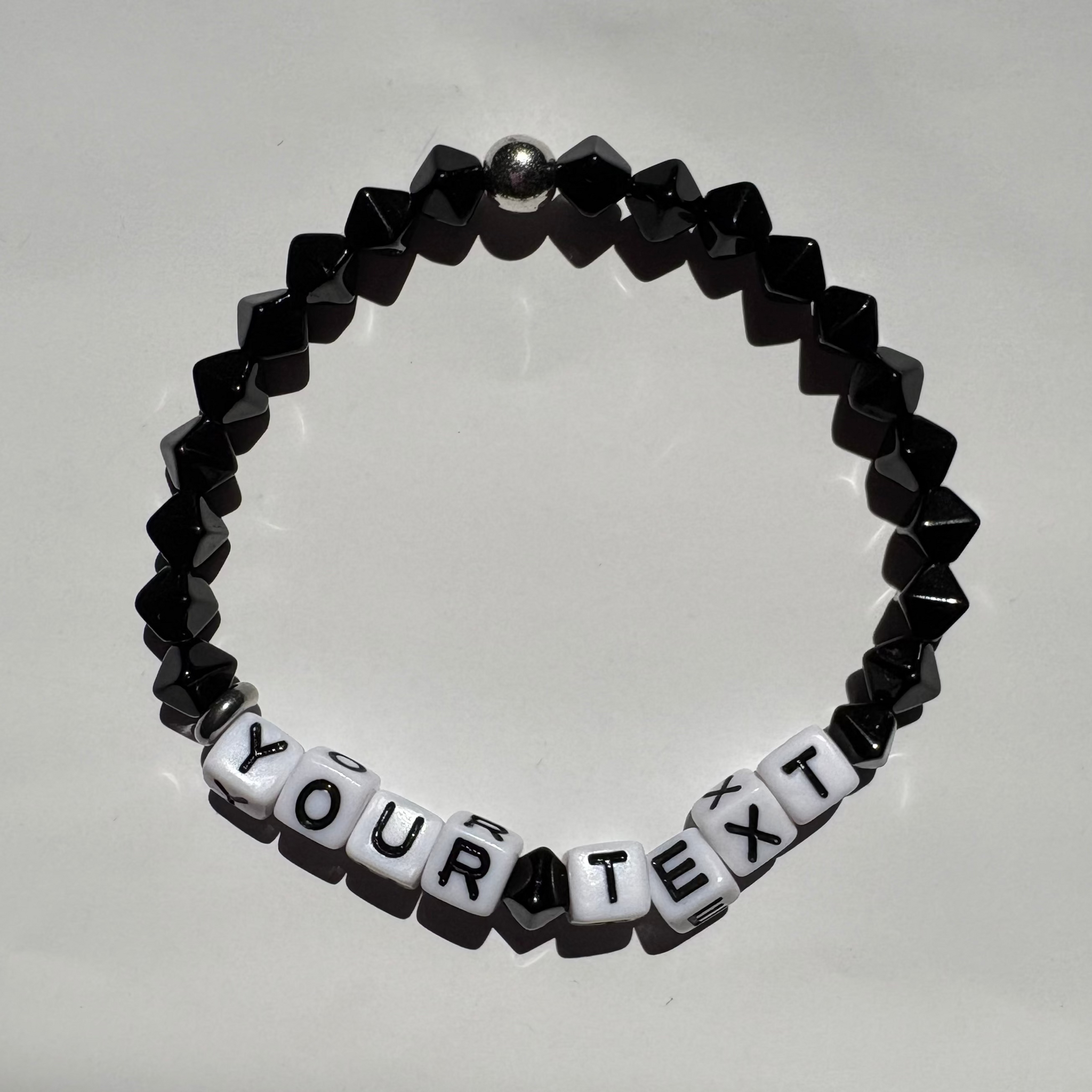 Black beaded bracelet with customizable text on a light gray background