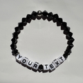 Black beaded bracelet with customizable text on a light gray background